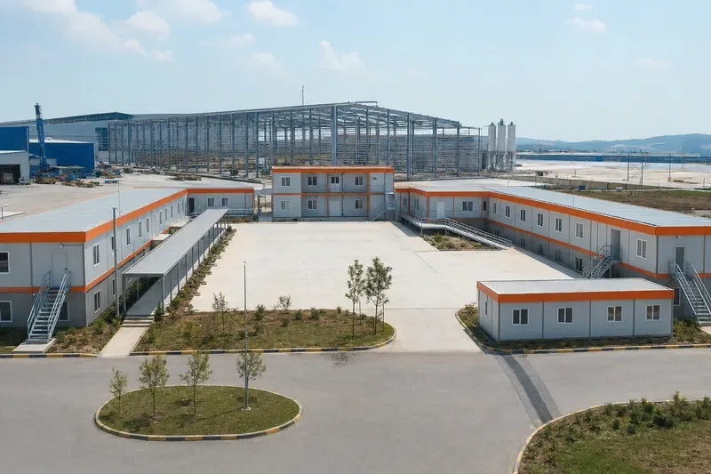 Yerleşkenin U planını ve endüstriyel saha bağlantısını gösteren genel görünüm.
